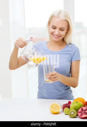 lächelnde Frau Gießen Fruchtsaft zu Hause Glas Stockfoto