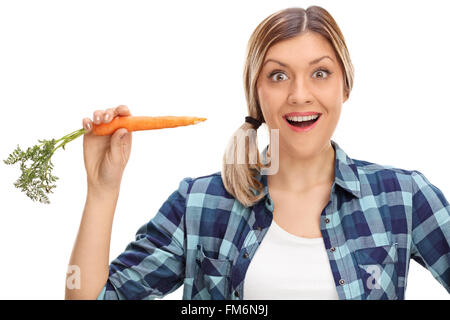 Erregte junge Frau eine Karotte zu essen und schaut in die Kamera, die isoliert auf weißem Hintergrund Stockfoto