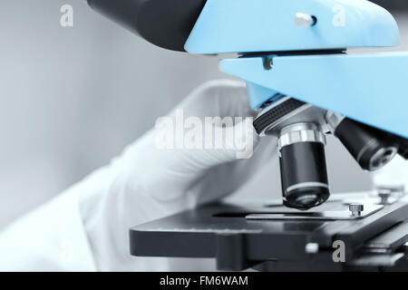 Nahaufnahme der Wissenschaftler Hand Einstellung Mikroskop Stockfoto