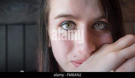 Eine schöne junge Frau scheint etwas nachdenklich werden, während sie in die Kamera schaut. Stockfoto