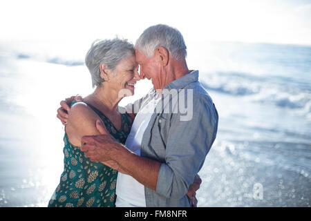 Älteres paar umarmt am Strand Stockfoto