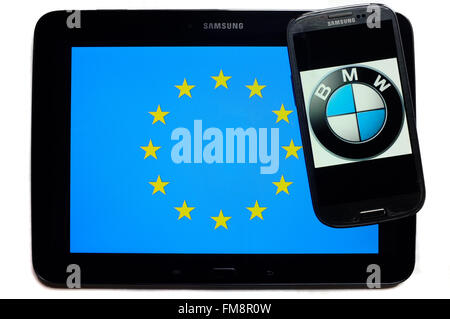 Ein Smartphone mit dem BMW Logo auf einem Tablet mit der EU-Flagge auf weißem Hintergrund fotografiert. Stockfoto