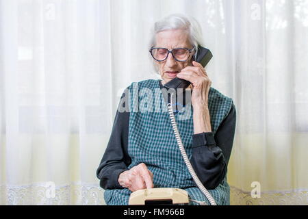 90 Jahre alte Frau mit dem Telefon im Haus Stockfoto