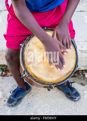 Kubanischen Jungen spielen Trommel vor seinem Haus auf der Straße in der Stadt von Regla über den Hafen von Havanna, Kuba. Stockfoto