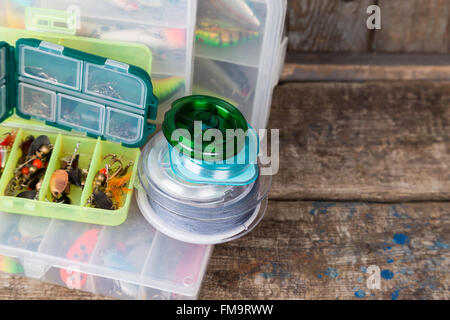 Angelgeräte, Köder und Köder in den Kästen auf Holzbalken Hintergrund für Outdoor-aktive Unternehmen Stockfoto