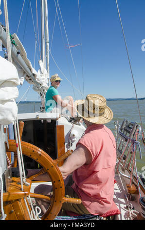Ein Ehepaar im Ruhestand auf ihrem Segelboot genießen Sie einen Moment der Ruhe an einem hellen Sonnentag mitten im See. Stockfoto