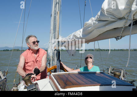 Ein älteres Paar genießt die Zeit zusammen auf ihren Ketch als der Mann bereitet die mainmast Segel zu heben. Stockfoto