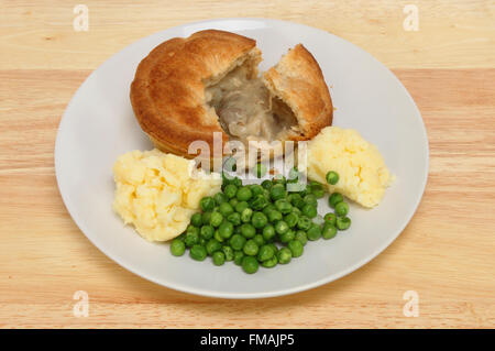 Huhn und Pilz-Pie mit Kartoffelpüree und Erbsen auf einem Teller auf einer hölzernen Tischplatte Stockfoto