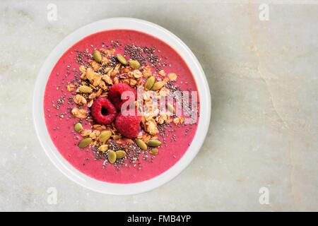 Smoothie-Schüssel mit Himbeeren, Müsli und Chia Samen auf weißem Granit Hintergrund, Draufsicht Stockfoto