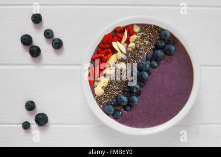 Nahrhafte smoothie Heidelbeere Schüssel mit Goji Beeren, Mandeln und Chia Samen auf weißem Holz mit frischen Beeren Stockfoto