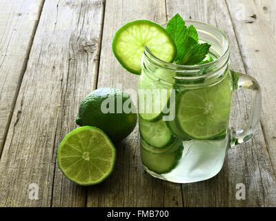 Detox Wasser mit Kalk und Gurken in einem Einmachglas vor einem rustikalen Holz Hintergrund Stockfoto