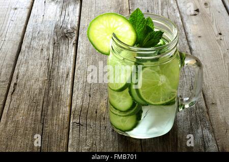 Detox Wasser mit Kalk und Gurken in einem Einmachglas vor einem rustikalen Holz Hintergrund Stockfoto