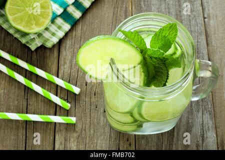 Detox Wasser mit Kalk und Gurken in ein Einmachglas. Nach unten gerichtete Blick auf Holz. Stockfoto