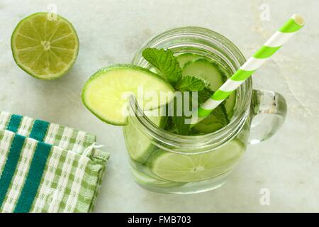 Detox Wasser mit Kalk und Gurken in ein Einmachglas mit Stroh. Nach unten gerichtete Blick auf weißem Marmor. Stockfoto