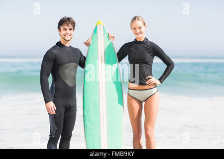 Paar mit Surfbrett stehend am Strand Stockfoto