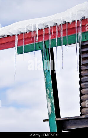 Winter-Detail mit Schmelzender Eiszapfen auf dem Dach des Chalet aus Holz Stockfoto