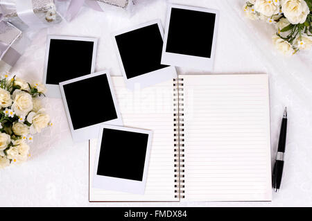 Hochzeit-Fotoalbum mit leeren Sofortbild-Prints auf Braut Spitze mit mehreren Silber Geschenke und Rosensträuße gelegt. Stockfoto