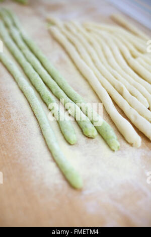 Runde Streifen von grünem und weißem Pasta Teig auf einer Holzfläche mit Grieß Mehl bestäubt. Stockfoto