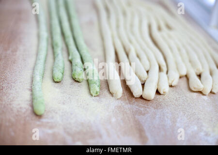 Runde Streifen von grünem und weißem Pasta Teig auf einer Holzfläche mit Grieß Mehl bestäubt. Stockfoto