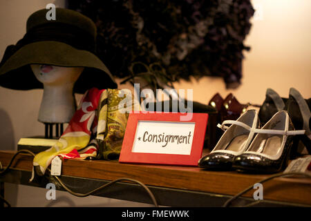 Eine Sendung Zeichen sitzt auf einem Regal in einem Bekleidungsgeschäft, umgeben von Artikel zum Verkauf. Stockfoto