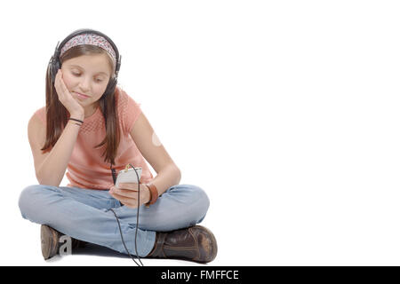 ein preteen Mädchen Musikhören mit seinem Smartphone, sitzt im Schneidersitz Stockfoto