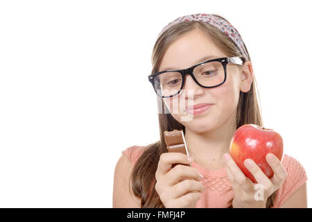 ein Preteen zögert zwischen Schokolade und einen Apfel Stockfoto