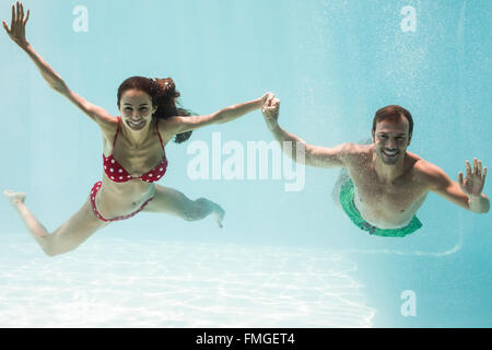 Porträt des Lächelns paar Hand in Hand beim Schwimmen Stockfoto