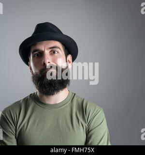 Skeptisch bärtige Hipster in die Kamera starrt. Kopfschuss Nahaufnahme Portrait über graue Studio-Hintergrund mit Vignette. Stockfoto