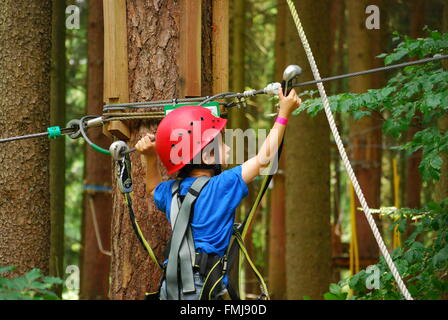 Ein Junge Haken seine Sicherheitsleine, ein neues Kabel in einem Hochseilgarten-parcours Stockfoto