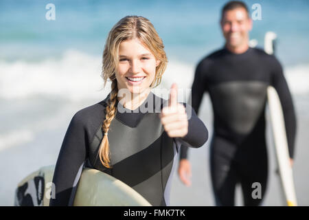 Glückliche Frau mit ihrem Daumen auftauchend Surfbrett Stockfoto