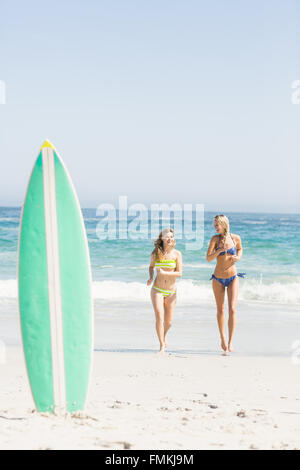 Surfbrett in Sand und zwei Frauen am Strand Stockfoto