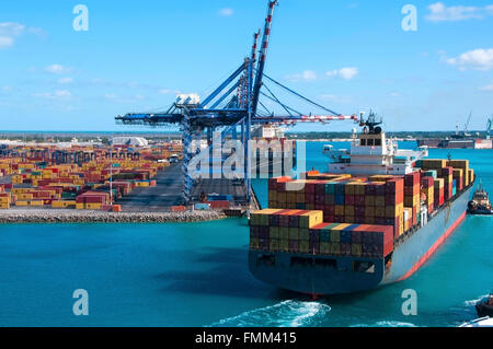 Hafen von Freeport Bahamas Container Werft mit Schwerarbeit Krane und ein Schiff kommen, um dock unterstützt von Schlepper Stockfoto