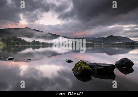 Ein nebliger Morgen auf Grasmere im Lake District, kurz nach Sonnenaufgang mit ein wenig Farbe in den Himmel als der Nebel beginnt t Stockfoto