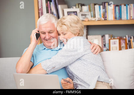 Aufgeregt senior Frau umarmt ihr Ehemann während mit laptop Stockfoto