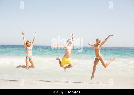 Glückliche junge Freunde springen am Strand Stockfoto