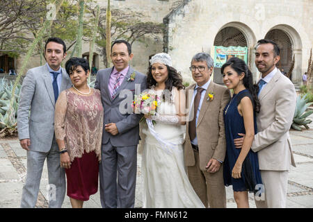 Mexikanische Hochzeitsgesellschaft posieren für Porträt auf der Kirche Santo Domingo Plaza mit lächelnden Braut hält kleine Strauß Frühlingsblumen Stockfoto