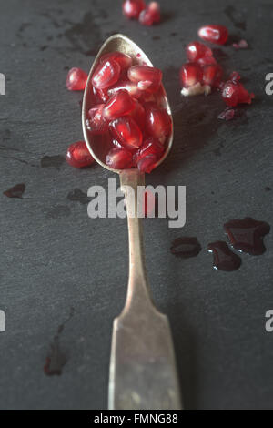 Granatapfel Samen auf silbernen Löffel, Schiefer Stockfoto