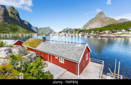 Rotes Haus mit Blick über den Fjord im Sommer, Reine Rorbuer Rorbu Fischerdorf, Reinefjord, Moskenesøy, Lofoten, Norwegen Stockfoto