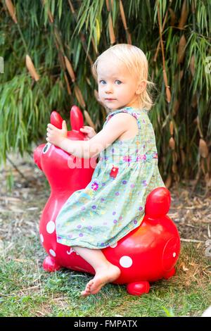 Kleinkind, Mädchen sitzen auf einem Pferd Rubber Ball springen Stockfoto