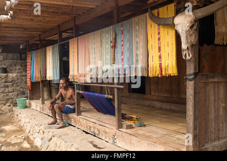 Ngada Mann sitzen auf der Veranda mit Ikat-Stoffe und Büffelhorn, traditionelles Dorf Bena, Bajawa, Insel Flores, Indonesien Stockfoto