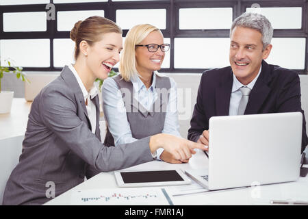 Geschäftsleute, die während der Diskussion über Laptop lächelnd Stockfoto