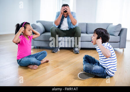 Verärgert Vater sitzt auf dem Sofa, während Kinder kämpfen Stockfoto