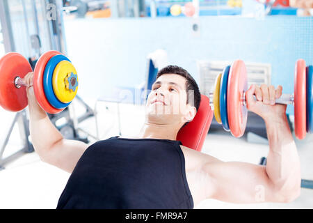 Hübscher junger Mann Heben schwerer Hanteln im Fitnessstudio Stockfoto