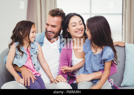 Eltern, die lächelnd mit Töchtern auf Sofa sitzend Stockfoto