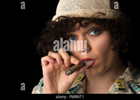 Hübsche junge kaukasischen Frau Rauchen Zigarre mit kommen hierher Blick auf Kamera und dunklem Hintergrund Stockfoto
