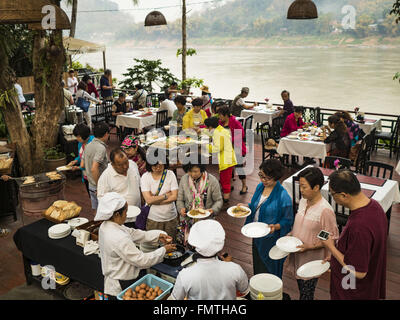 Luang Prabang, Luang Prabang, Laos. 11. März 2016. Touristen in einem Hotel-Frühstück vom Buffet in Luang Prabang. Der Mekong ist im Hintergrund. Luang Prabang wurde 1995 zum UNESCO-Weltkulturerbe ernannt. Der Umzug gespeichert koloniale Architektur der Stadt, aber die Explosion des Massentourismus hat ein Tribut an die Seele der Stadt. Laut einer aktuellen Studie geht jetzt ein kleines Grundstück, das für $8.000 vor drei Jahren verkauft für $120.000. Viele langjährige Bewohner sind Verkauf ihrer Häuser und Umzug in kleine Entwicklungen rund um die Stadt. Die alten Häuser sind dann in Pensionen, Resta umgewandelt. Stockfoto