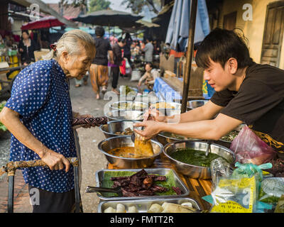 Luang Prabang, Luang Prabang, Laos. 13. März 2016. Ein Markt-Anbieter verkauft Lao Currys eine ältere Käufer auf dem Markt in Luang Prabang. Luang Prabang wurde 1995 zum UNESCO-Weltkulturerbe ernannt. Der Umzug gespeichert koloniale Architektur der Stadt, aber die Explosion des Massentourismus hat ein Tribut an die Seele der Stadt. Laut einer aktuellen Studie geht jetzt ein kleines Grundstück, das für $8.000 vor drei Jahren verkauft für $120.000. Viele langjährige Bewohner sind Verkauf ihrer Häuser und Umzug in kleine Entwicklungen rund um die Stadt. Die alten Häuser werden dann in Pensionen und Restaurants umgewandelt ein Stockfoto