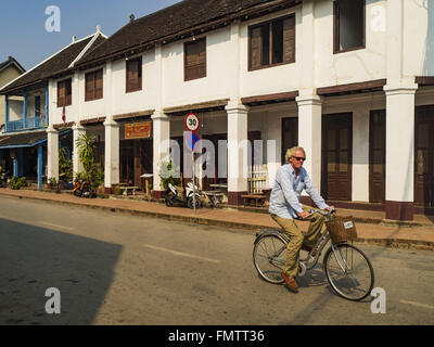 Luang Prabang, Luang Prabang, Laos. 13. März 2016. Ein Tourist Pedalen vorbei an einem französischen Kolonialgebäude, die in einem Spa in Luang Prabang umgewandelt wurde. Luang Prabang wurde 1995 zum UNESCO-Weltkulturerbe ernannt. Der Umzug gespeichert koloniale Architektur der Stadt, aber die Explosion des Massentourismus hat ein Tribut an die Seele der Stadt. Laut einer aktuellen Studie geht jetzt ein kleines Grundstück, das für $8.000 vor drei Jahren verkauft für $120.000. Viele langjährige Bewohner sind Verkauf ihrer Häuser und Umzug in kleine Entwicklungen rund um die Stadt. Die alten Häuser sind dann in Pensionen, Resta umgewandelt. Stockfoto