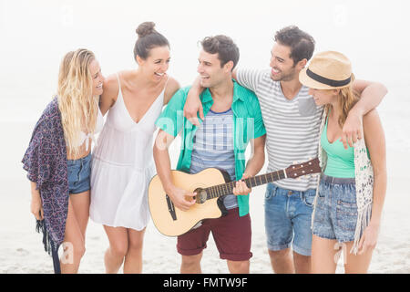 Gruppe von Freunden stehen am Strand mit einer Gitarre Stockfoto