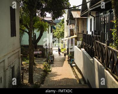 Luang Prabang, Luang Prabang, Laos. 13. März 2016. Eine Frau kreuzt eine restaurierte Gasse in eine Wohn-Abschnitt von Luang Prabang. Luang Prabang wurde 1995 zum UNESCO-Weltkulturerbe ernannt. Der Umzug gespeichert koloniale Architektur der Stadt, aber die Explosion des Massentourismus hat ein Tribut an die Seele der Stadt. Laut einer aktuellen Studie geht jetzt ein kleines Grundstück, das für $8.000 vor drei Jahren verkauft für $120.000. Viele langjährige Bewohner sind Verkauf ihrer Häuser und Umzug in kleine Entwicklungen rund um die Stadt. Die alten Häuser sind dann in Thermen, Pensionen und Restaurants umgewandelt. Die Stockfoto